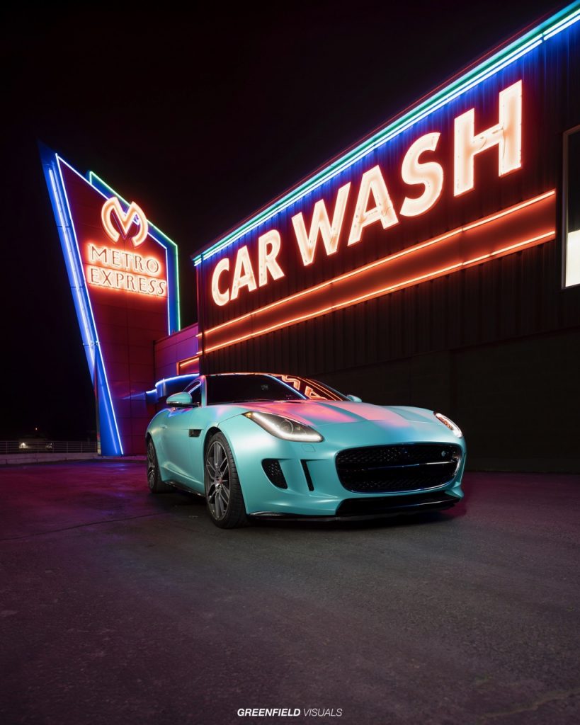 Auto mit Folierung der Farbe Matt Caribbean Mint vor Neonschild